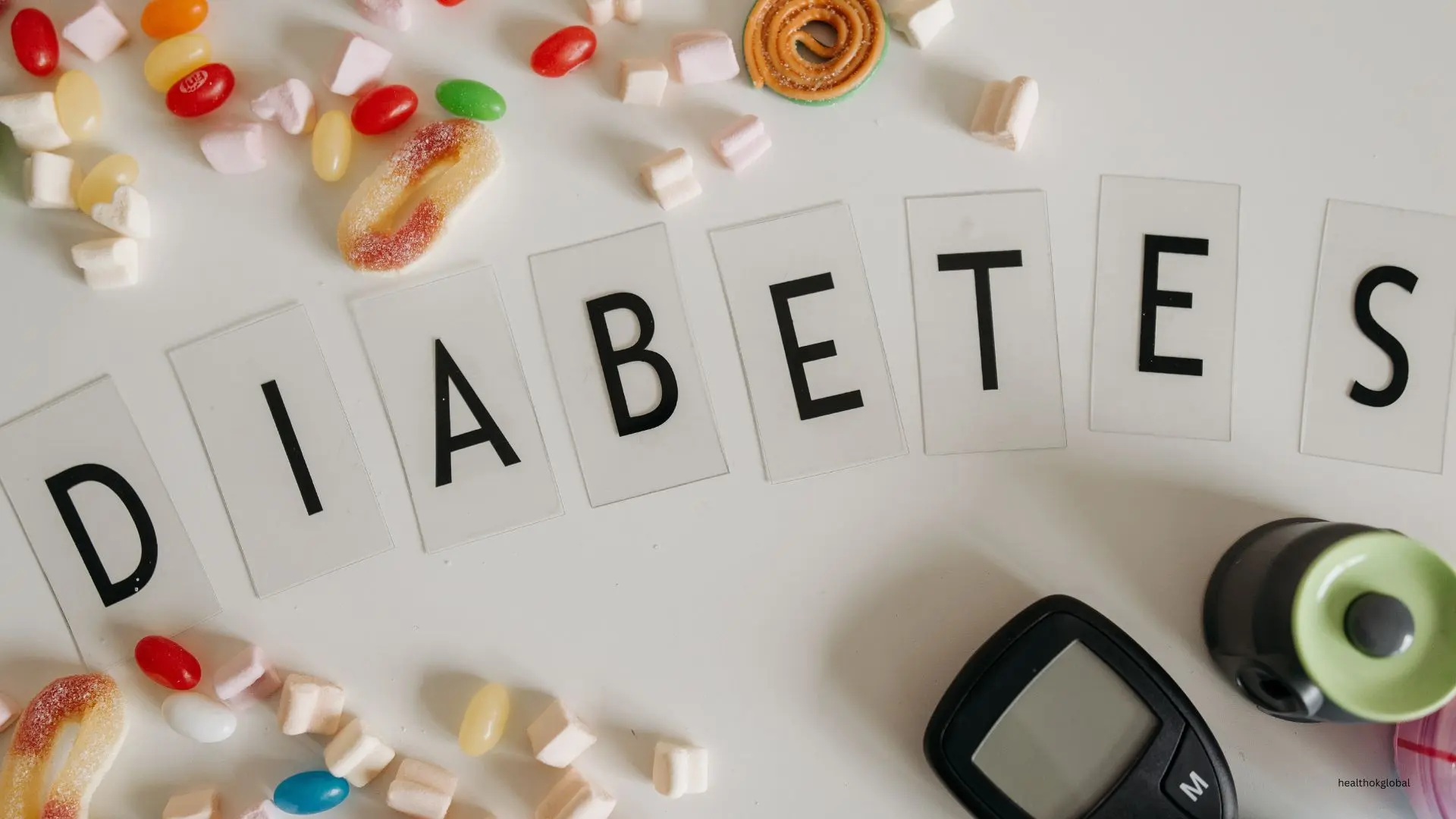 Diabetes concept with the word DIABETES displayed alongside colorful candies and blood sugar monitoring tools, emphasizing diabetes management and awareness.