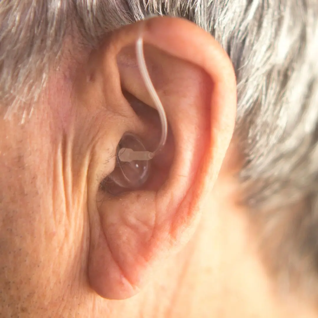 Close-up view of a senior person's ear with a discreet hearing aid device, showcasing modern hearing aid technology for improved hearing.